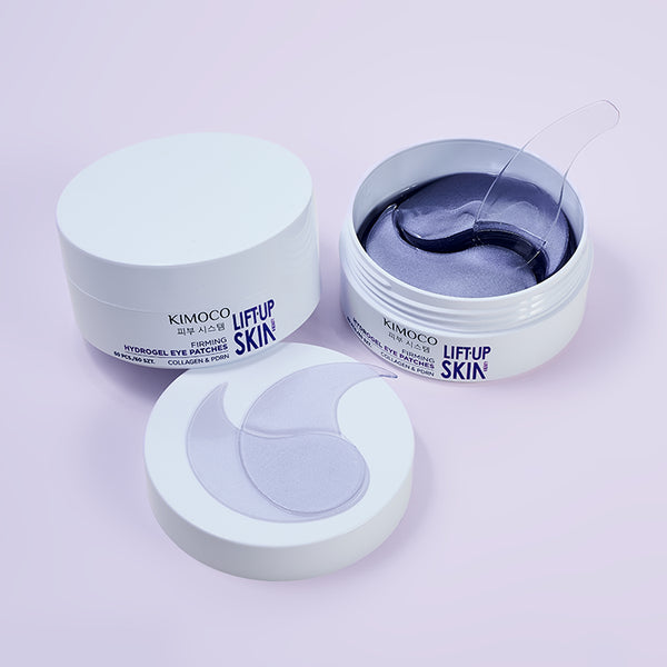 Z lewej zamknięty pojemnik "Kimoco Lift-Up Skin Firming Hydrogel Eye Patches", z prawej otwarty pojemnik z fioletowymi płatkami pod oczy i jednym uniesionym, na dole odłożona pokrywka z widocznymi płatkami przyklejonymi od wewnątrz, na jasnoróżowym tle.